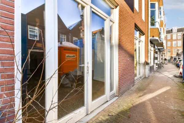 Straatbeeld van de Korte Schimmelstraat met rode bakstenen gevels en grote glazen deuren.